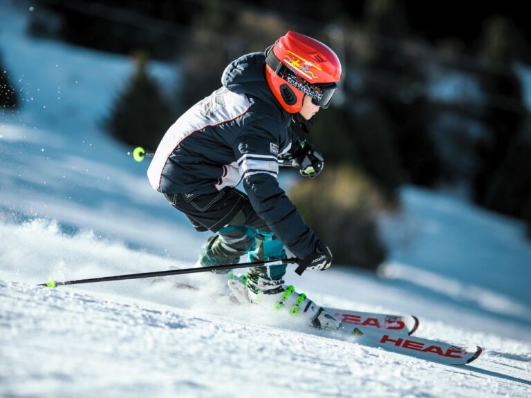 A boy skiing in Denmark wearing helmet, gloves, and poles