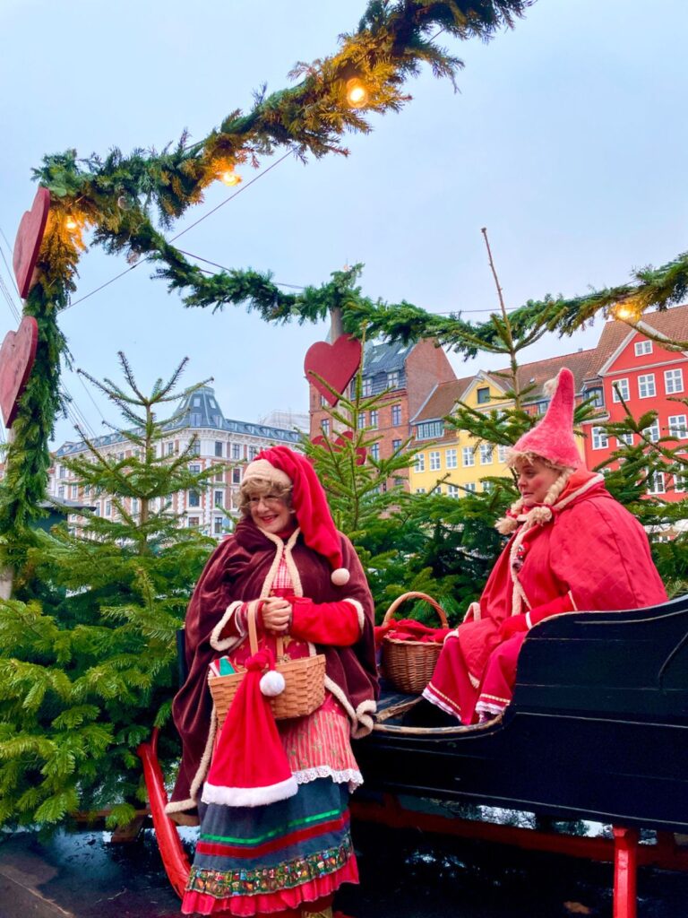 Christmas Celebrations in Copenhagen at Nyhavn where two grandma are giving Christmas gifts to passing Children