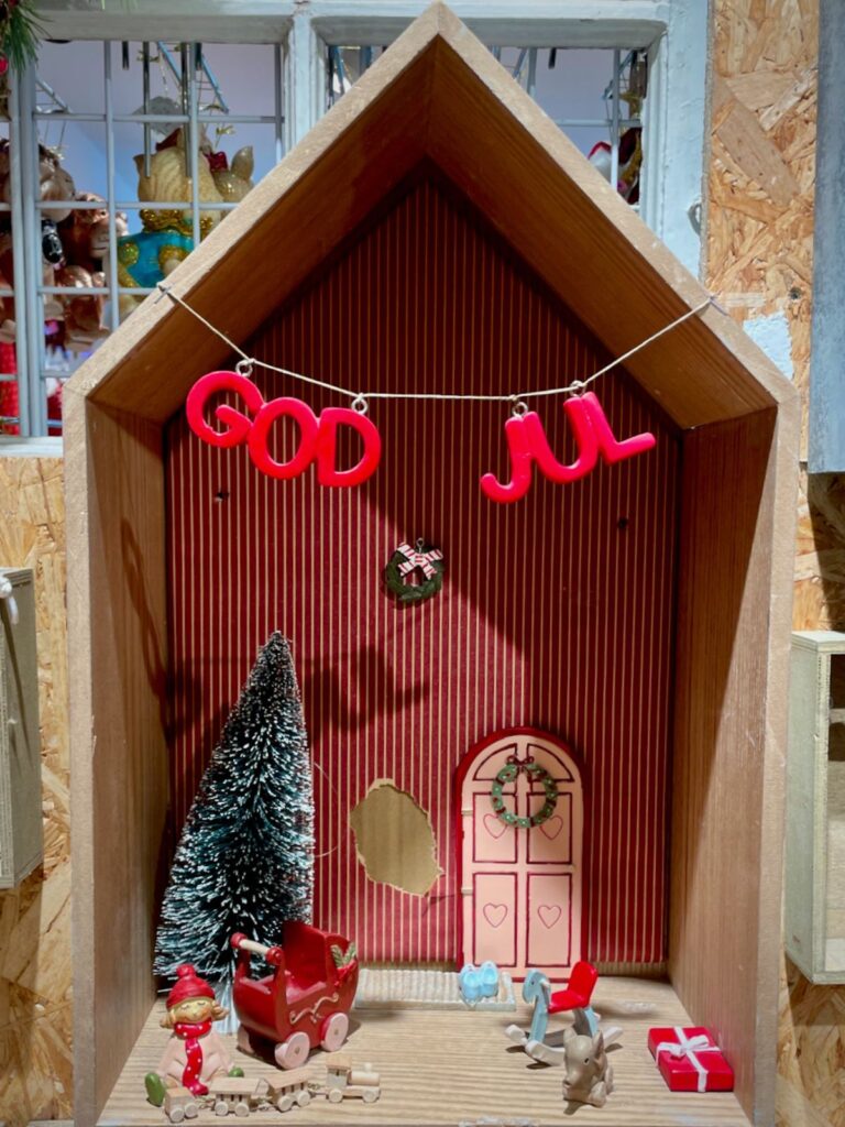 Toys decorated inside a house shaped frame with Glædelig Jul or Merry Christmas garland