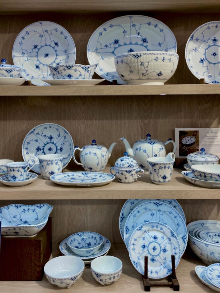 Royal Copenhagen plates, tea pots, bowls, cups, and saucer arranged on a shelf