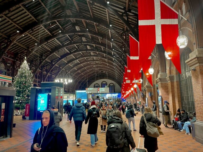 Tourists and locals walking in a busy train station in Copenhagen showcasing various outfits giving you an idea of what to wear in Denmark