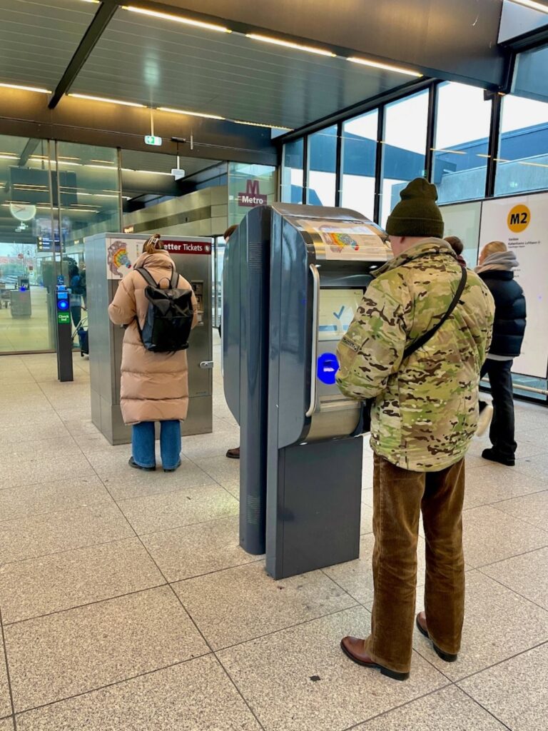 People buying M2 Metro tickets near the Copenhagen Airport metro station