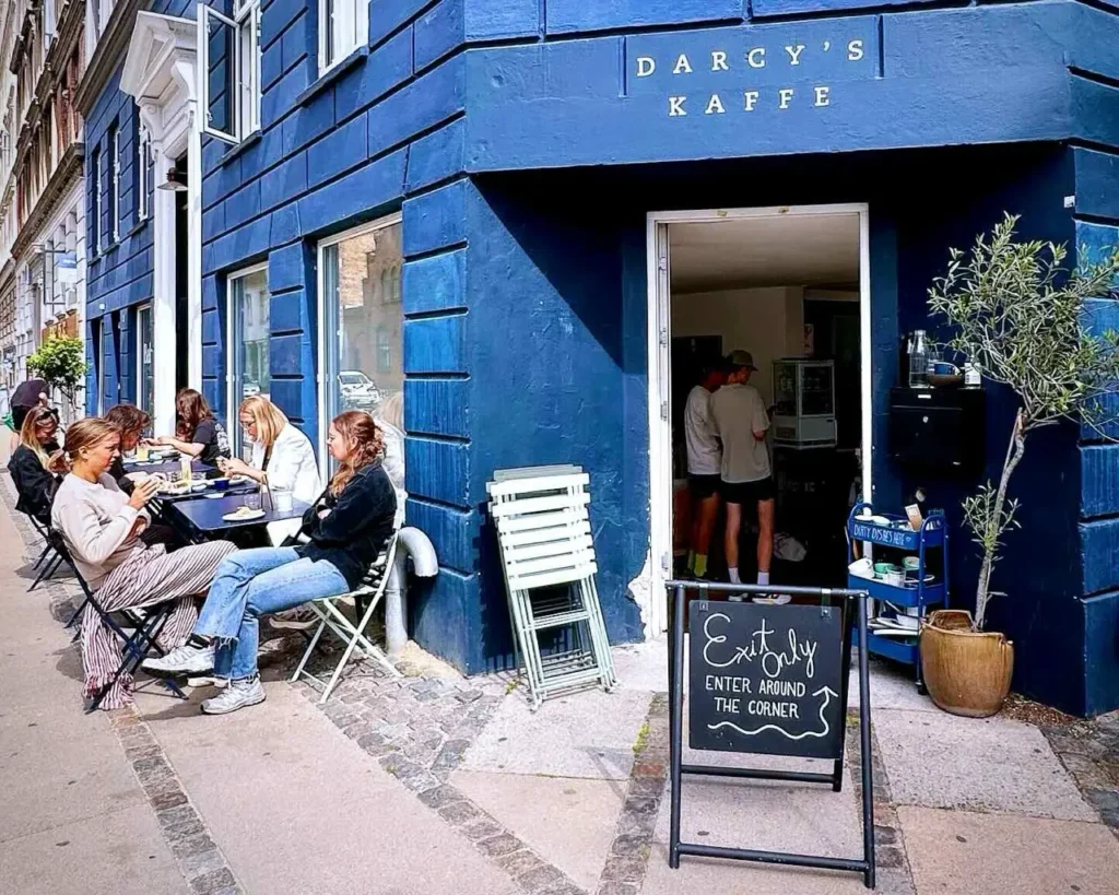 Few people eating and drinking coffee at the entrance of Darcy Cafe