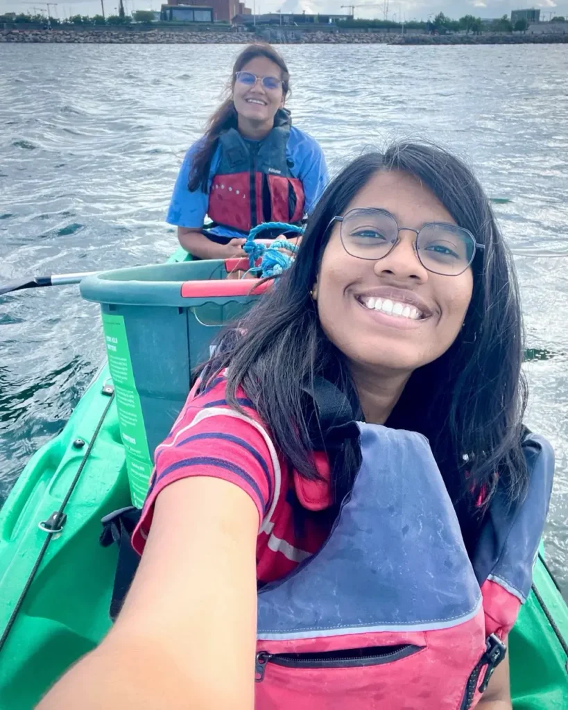 Agalya and her friend cleaning the sea on a green kayak