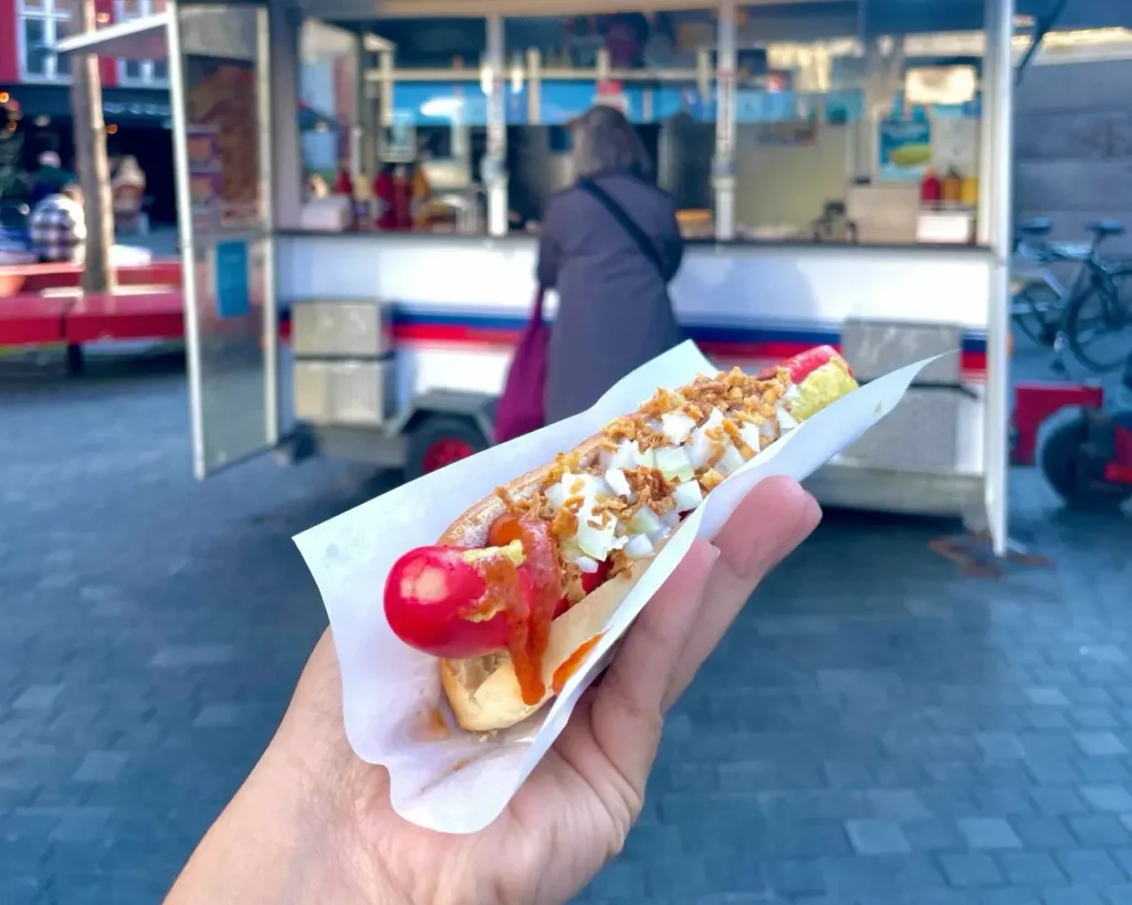 Agalya holding a Pølsemand, Danish hotdog
