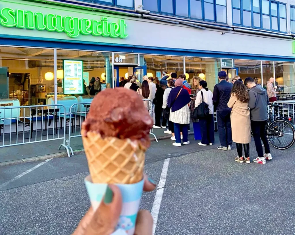 Agalya holding ice cream in front of Ismageriet ice cream shop flooded with a long queue